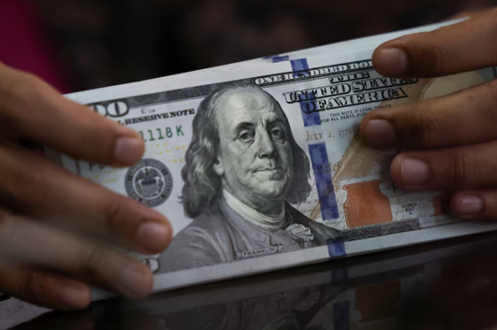 An employee handling US dollar banknotes at a money changer in Jakarta, Indonesia