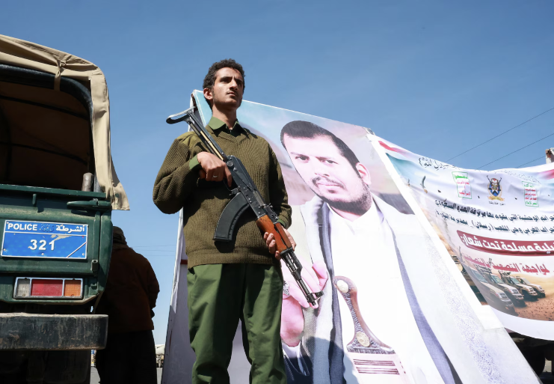 Houthi security personnel stands near a poster of leader Abdul-Malik al-Houthi during a solidarity rally in Sanaa, Yemen, October 7, 2026