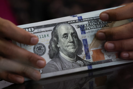 An employee holds US dollar banknotes at a money changer in Jakarta, Indonesia, April 9, 2025